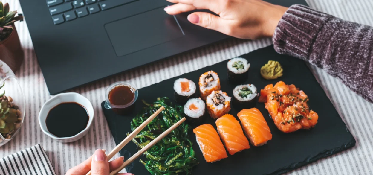 Working on a laptop and eating sushi