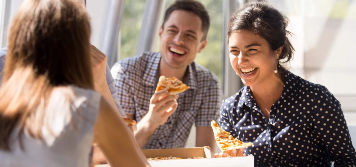 People eating pizza and smiling